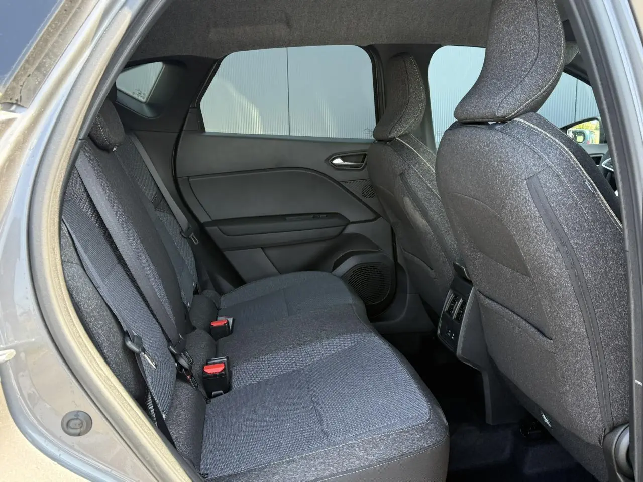 Vue intérieure arrière côté gauche du Renault Captur gris Cassiopée, montrant les sièges tissu et les portières.