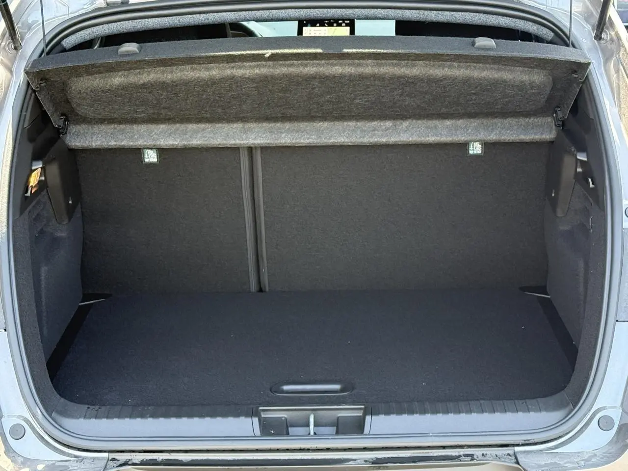 Coffre ouvert vu de l'arrière d'un Renault Captur gris Cassiopée, espace de chargement vide et propre.