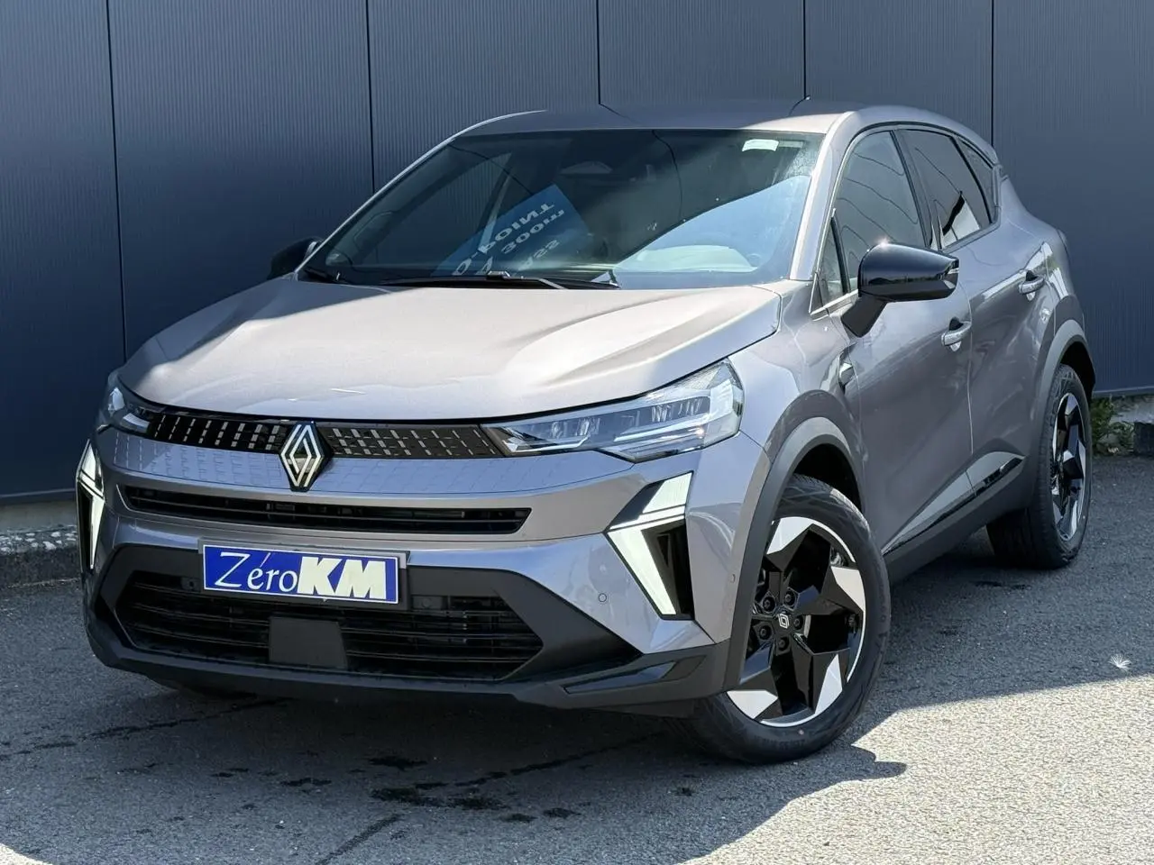 Renault Captur 2026 gris Cassiopée en 3/4 avant droit, avec jantes 18 pouces Black Hole et calandre moderne.