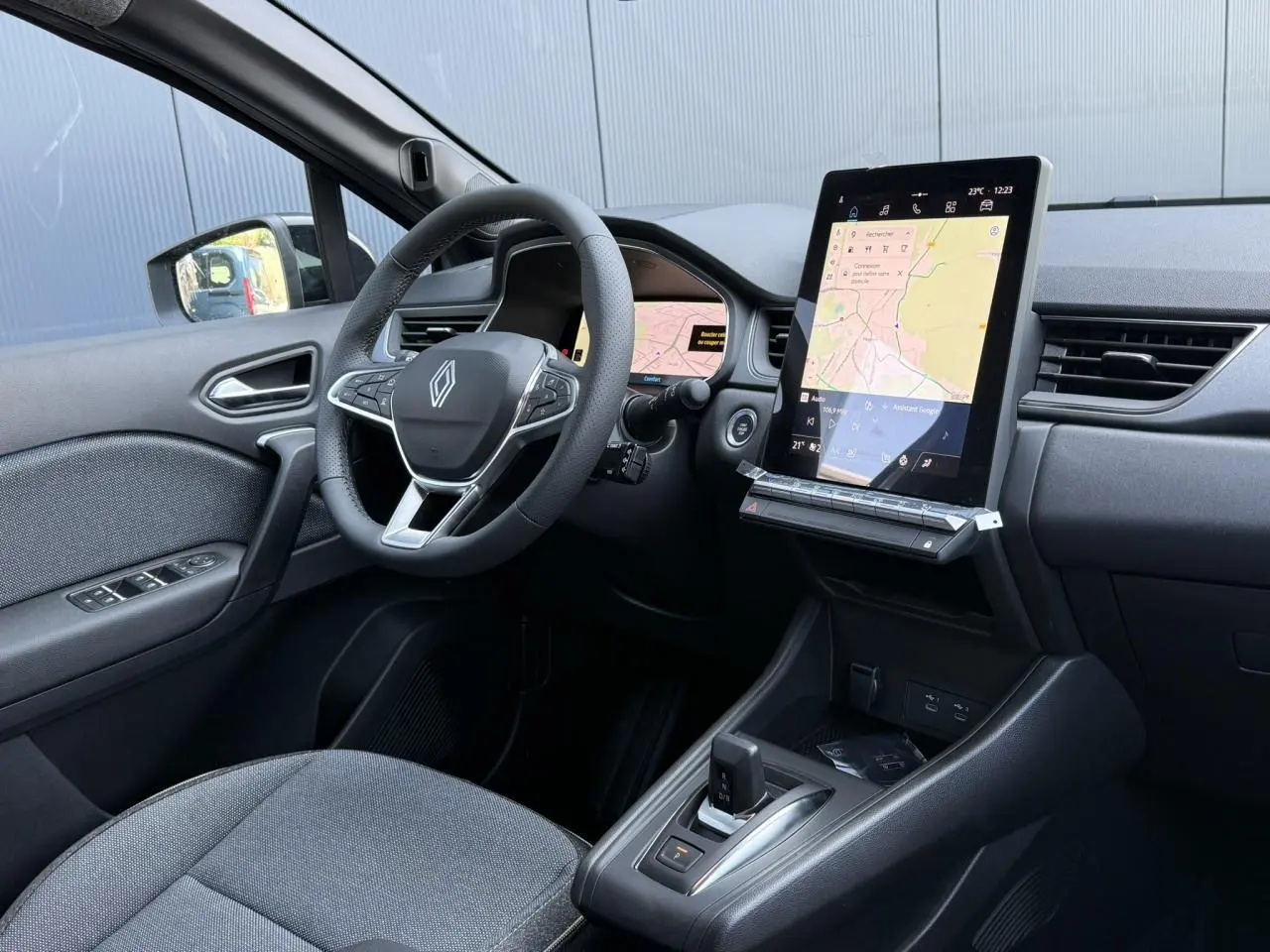 Vue intérieure côté conducteur du Renault Captur gris Cassiopée, avec volant multifonction et grand écran tactile vertical.
