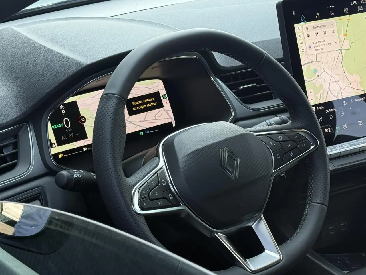 Vue rapprochée du volant noir perforé du Renault Captur 2026 avec tableau de bord numérique et écran tactile central.