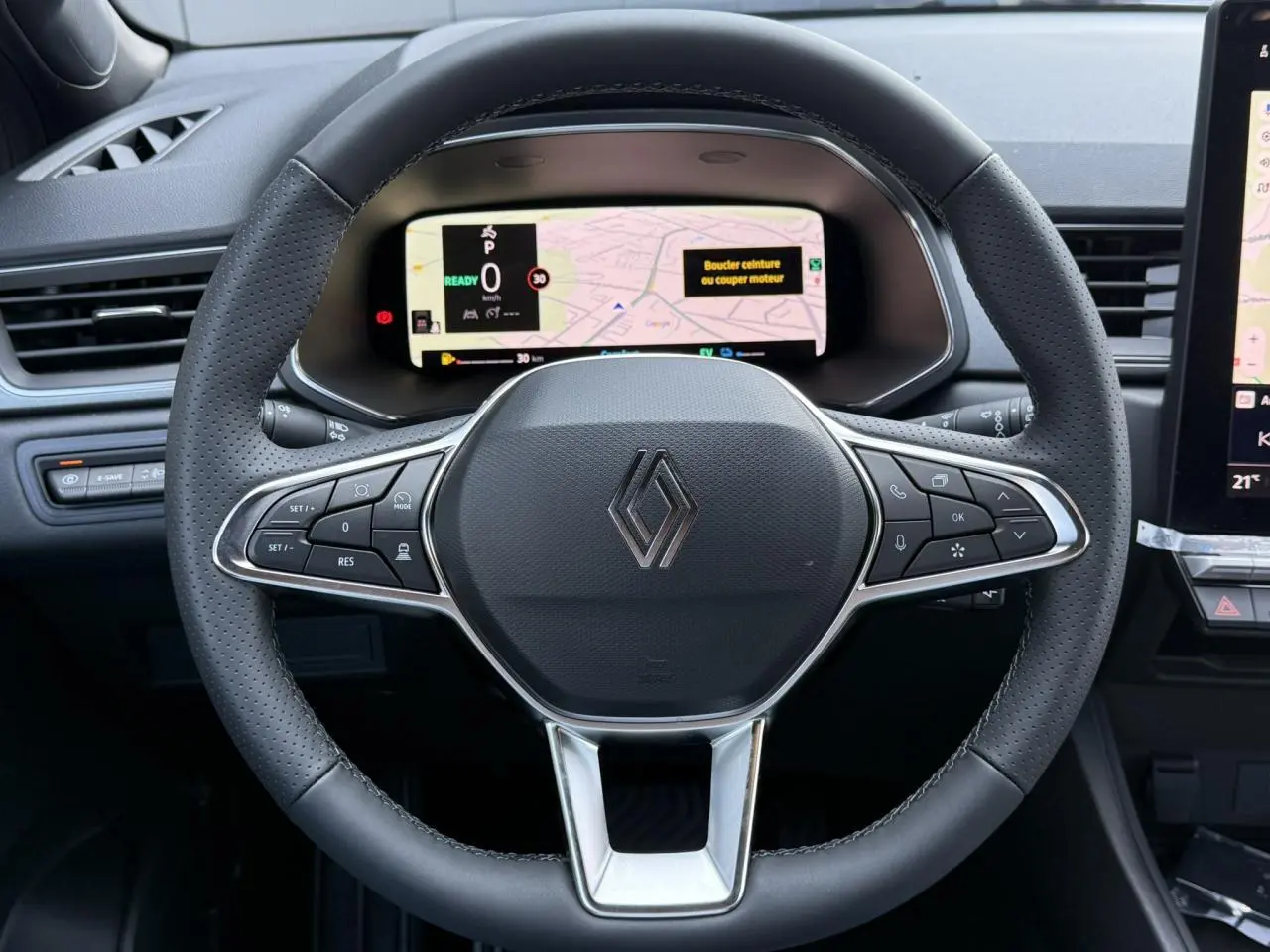 Vue rapprochée du volant noir perforé de Renault Captur 2026 avec tableau de bord numérique et commandes intégrées.