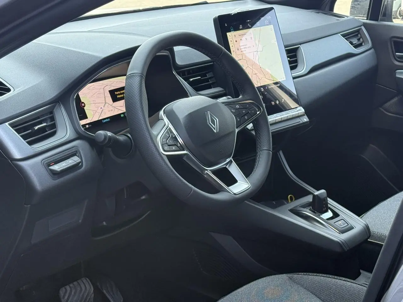 Vue intérieure côté conducteur du Renault Captur 2026, volant multifonction et grand écran tactile central.