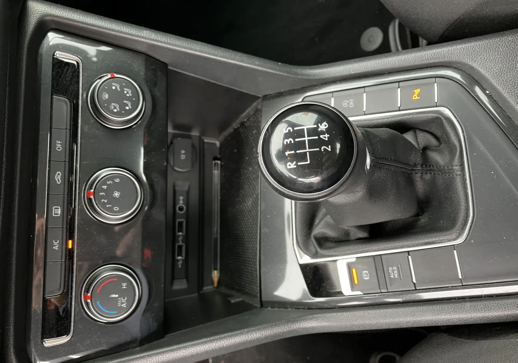 Gros plan sur la console centrale noire du Volkswagen Tiguan 2018 avec levier de vitesse manuel et commandes de climatisation.