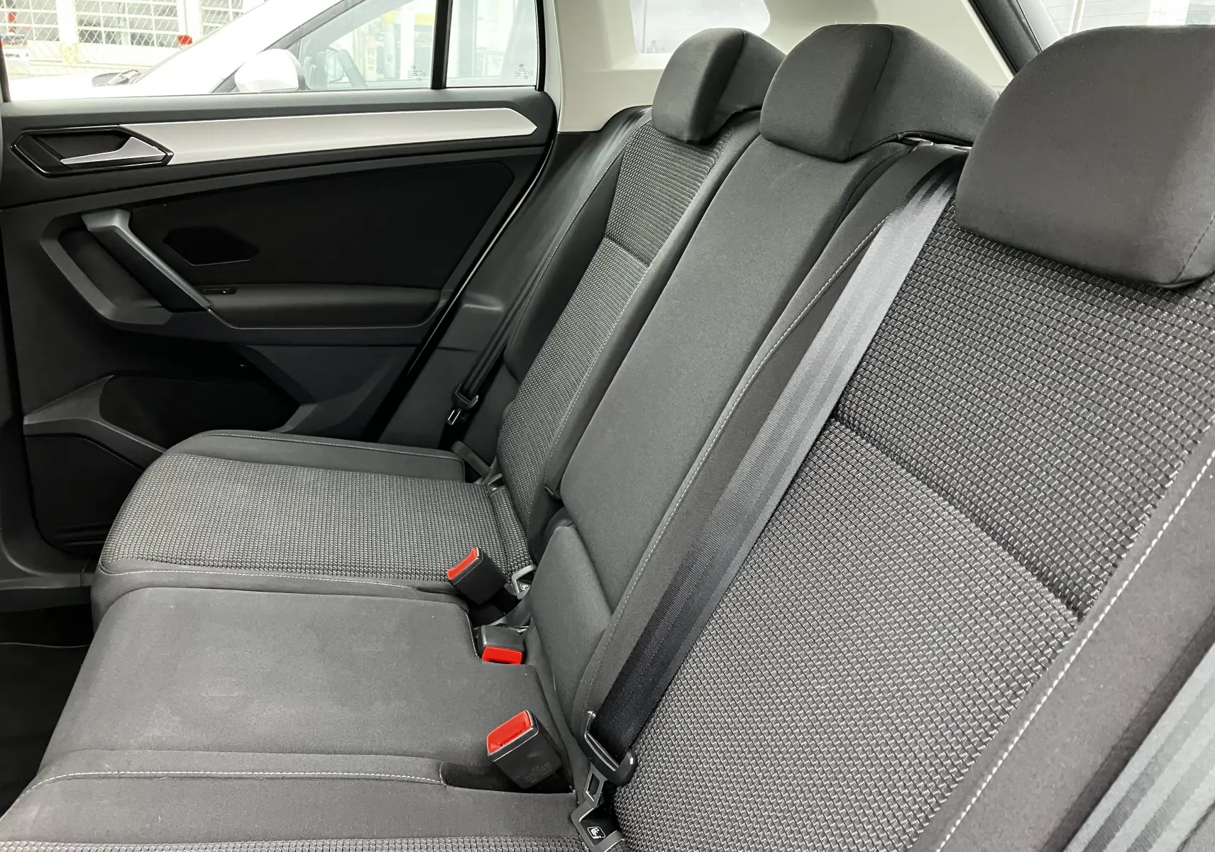 Vue intérieure côté gauche des sièges arrière gris foncé du Volkswagen Tiguan 2018, avec ceintures de sécurité visibles.
