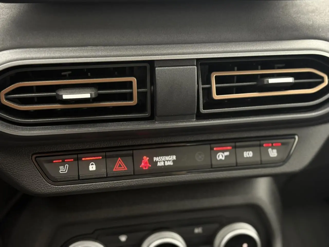 Gros plan sur les aérateurs et les commandes chauffantes du tableau de bord de la Dacia Sandero Stepway gris schiste.