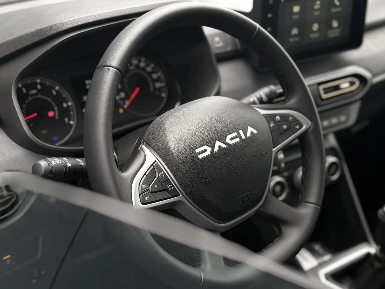 Vue rapprochée du volant noir de la Dacia Sandero Stepway 2025 avec commandes intégrées et tableau de bord numérique.