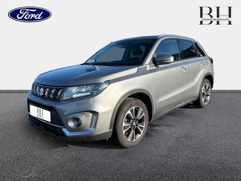 Suzuki Vitara Galactic Gray métallisé en 3/4 avant droit, avec calandre chromée et jantes alu distinctives.