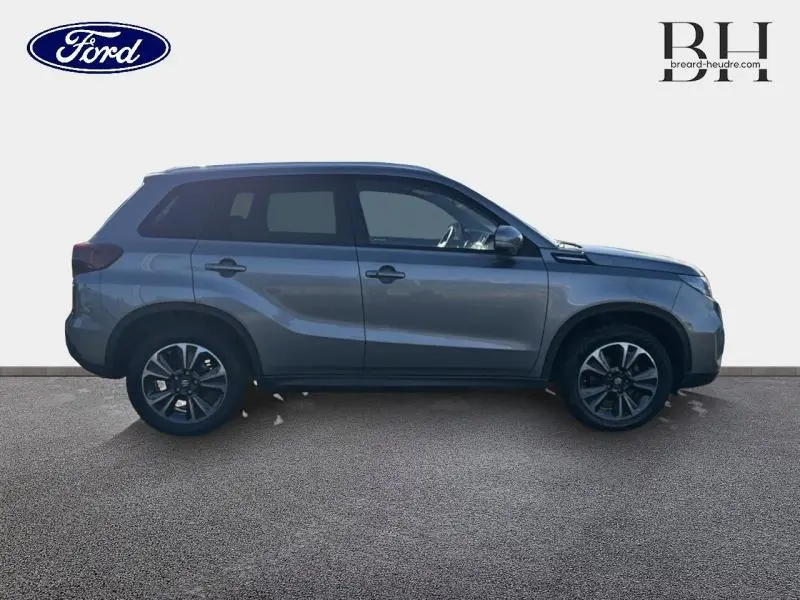 Profil côté gauche du Suzuki Vitara 1.4 Boosterjet Hybrid 2022 en Galactic Gray métallisé, avec jantes alu noires.
