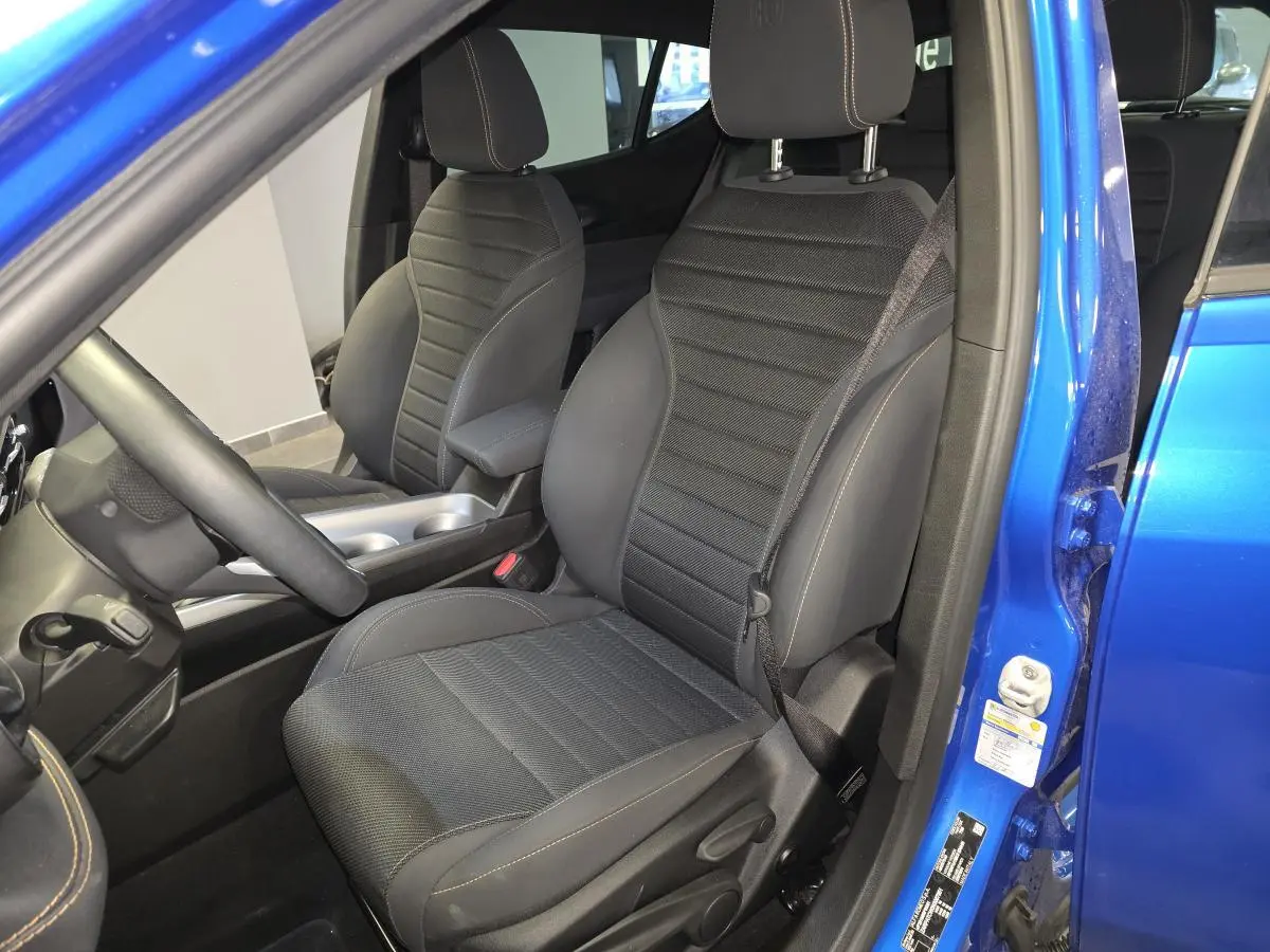 Vue intérieure côté conducteur de l'Alfa Romeo Tonale bleu 2024, siège tissu noir Carbone avec surpiqûres beige.