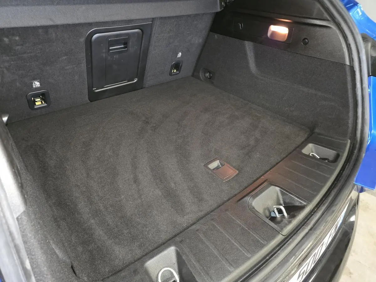 Coffre ouvert vu de dessus d’une Alfa Romeo Tonale bleu 2024, montrant un espace de rangement noir et un éclairage intérieur.