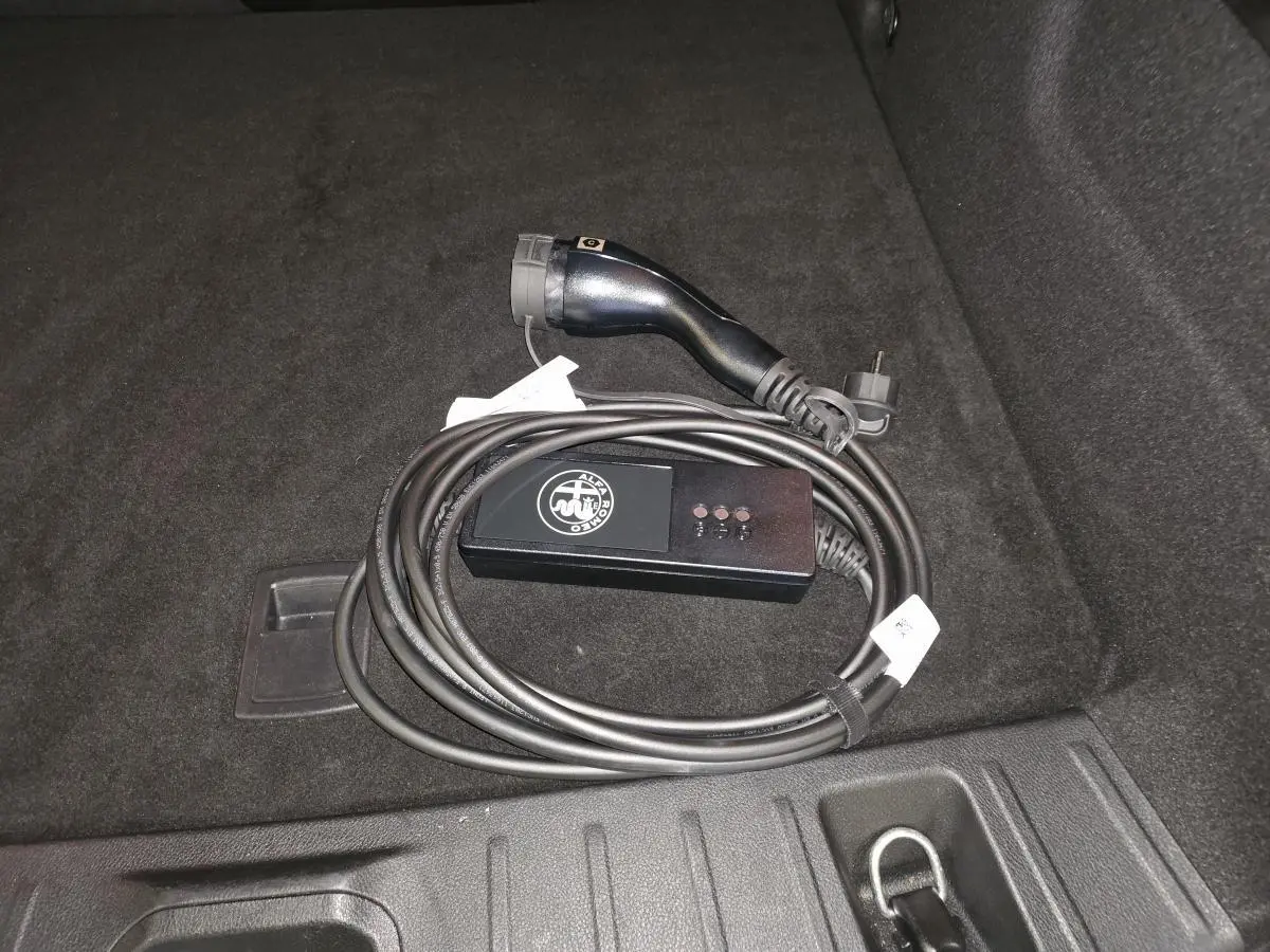 Câble de recharge mode 2 Alfa Romeo Tonale 1.3 PHEV 280 TI Q4 posé dans le coffre au revêtement noir.