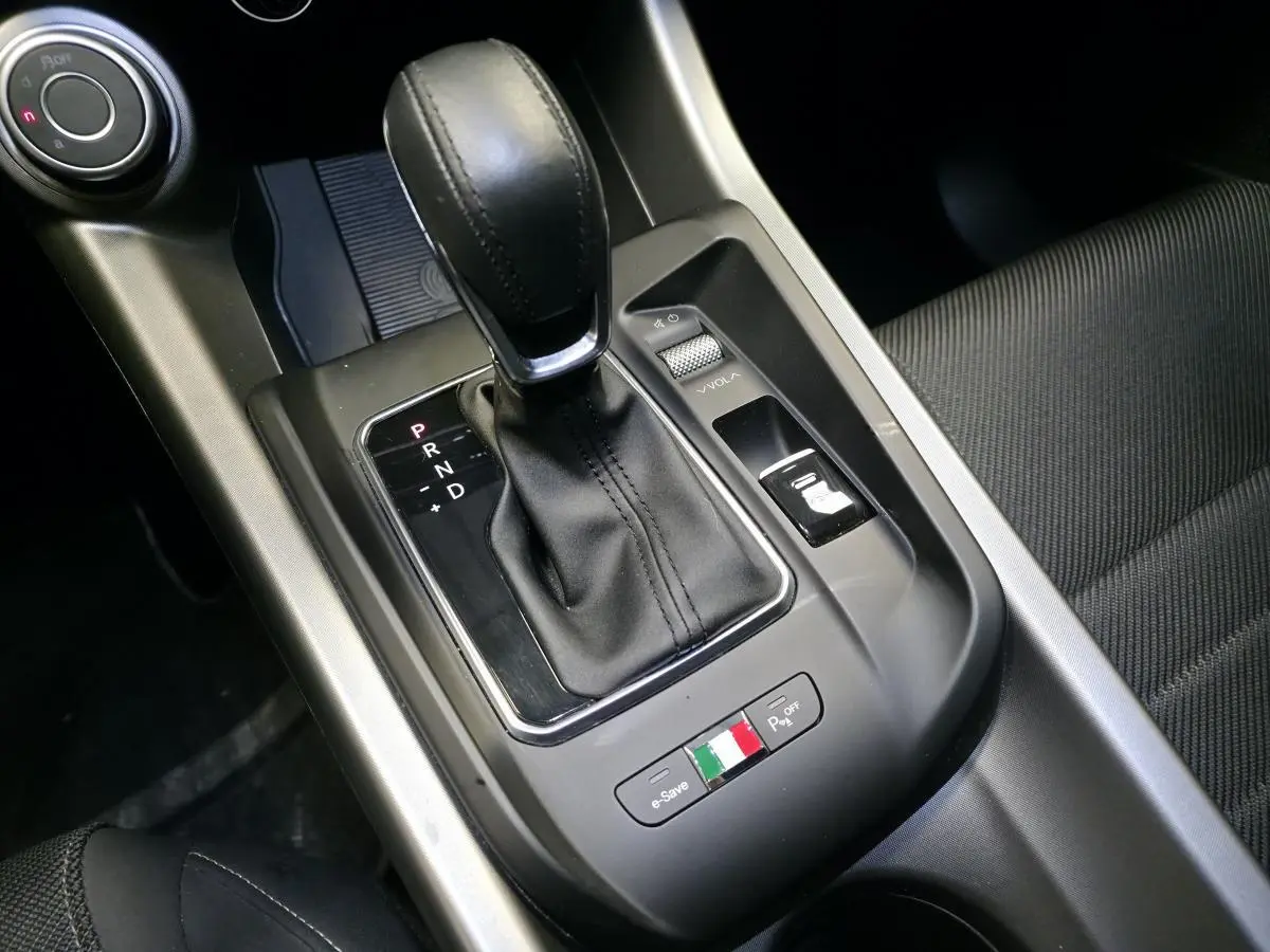 Gros plan sur la console centrale de l'Alfa Romeo Tonale 2024, levier de vitesses noir et logo tricolore italien.