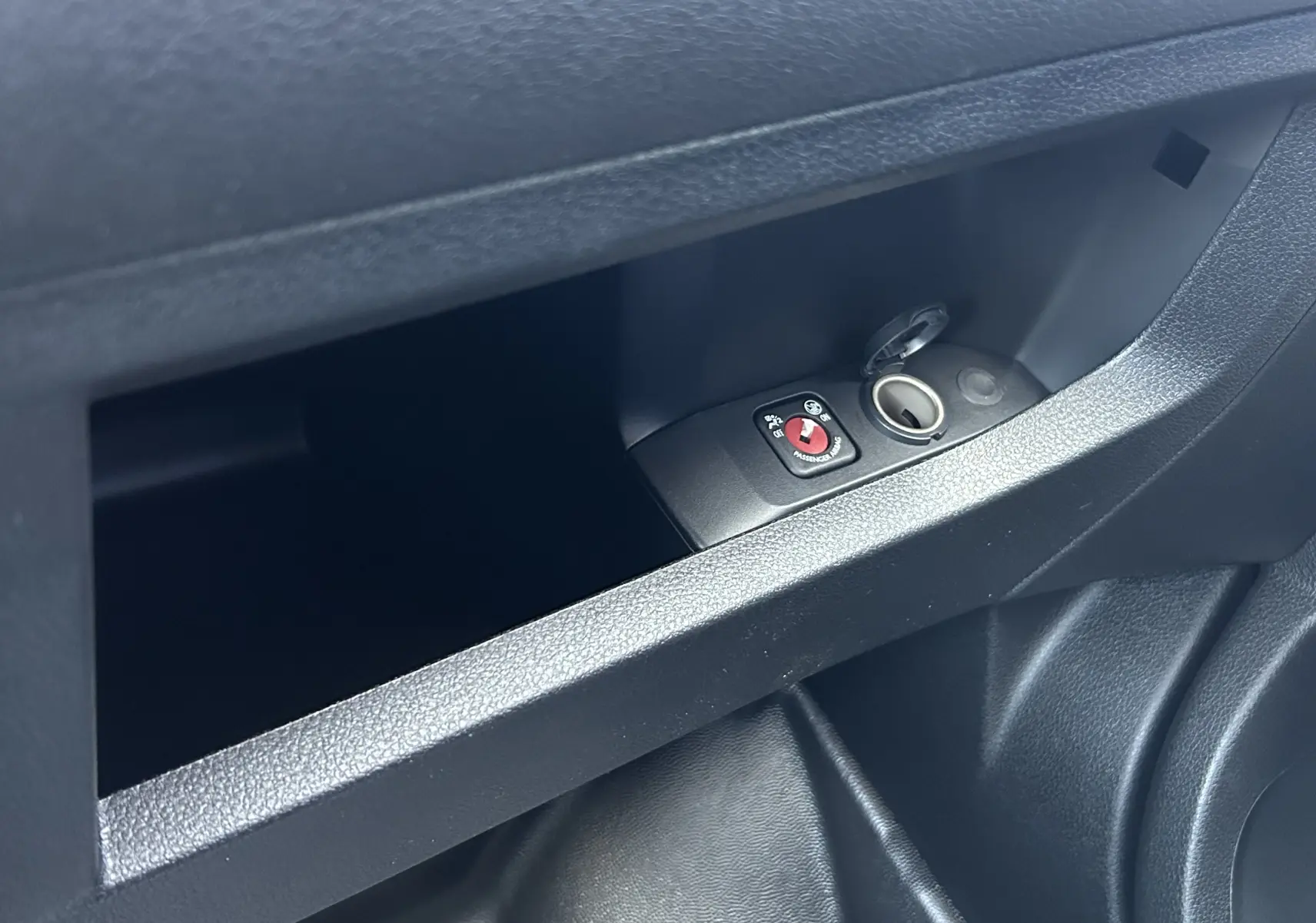Gros plan sur la prise 12V et le bouton de désactivation de l'airbag passager dans le rangement intérieur du Citroën Jumpy Cabine Approfondie noir.