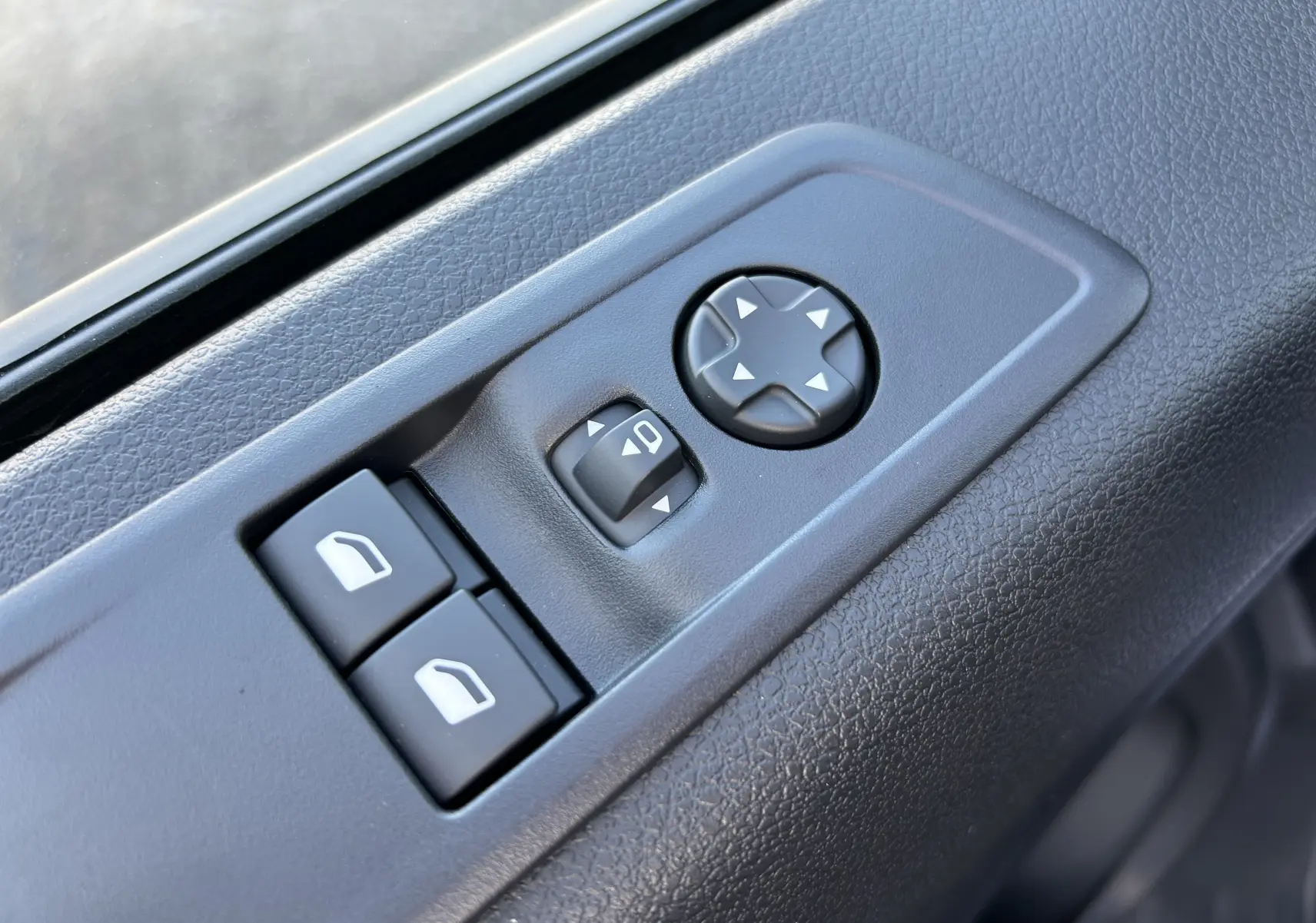 Gros plan sur les commandes de réglage des rétroviseurs et des vitres côté conducteur d’un Citroën Jumpy Cabine Approfondie noir.