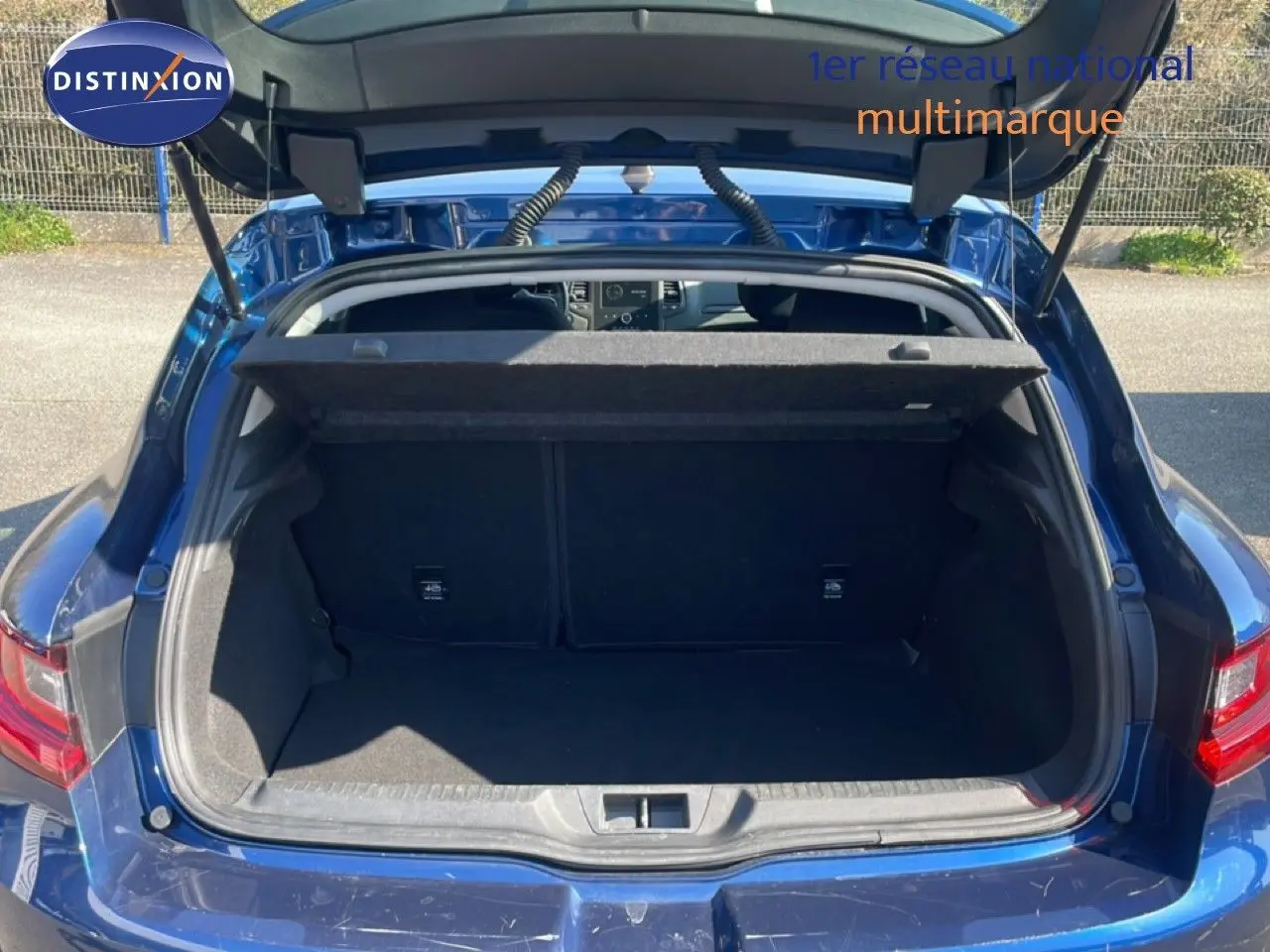 Coffre ouvert vu de l'arrière d'une Renault Mégane 1.3 TCE 140ch Business bleu cosmos métal, intérieur noir visible.