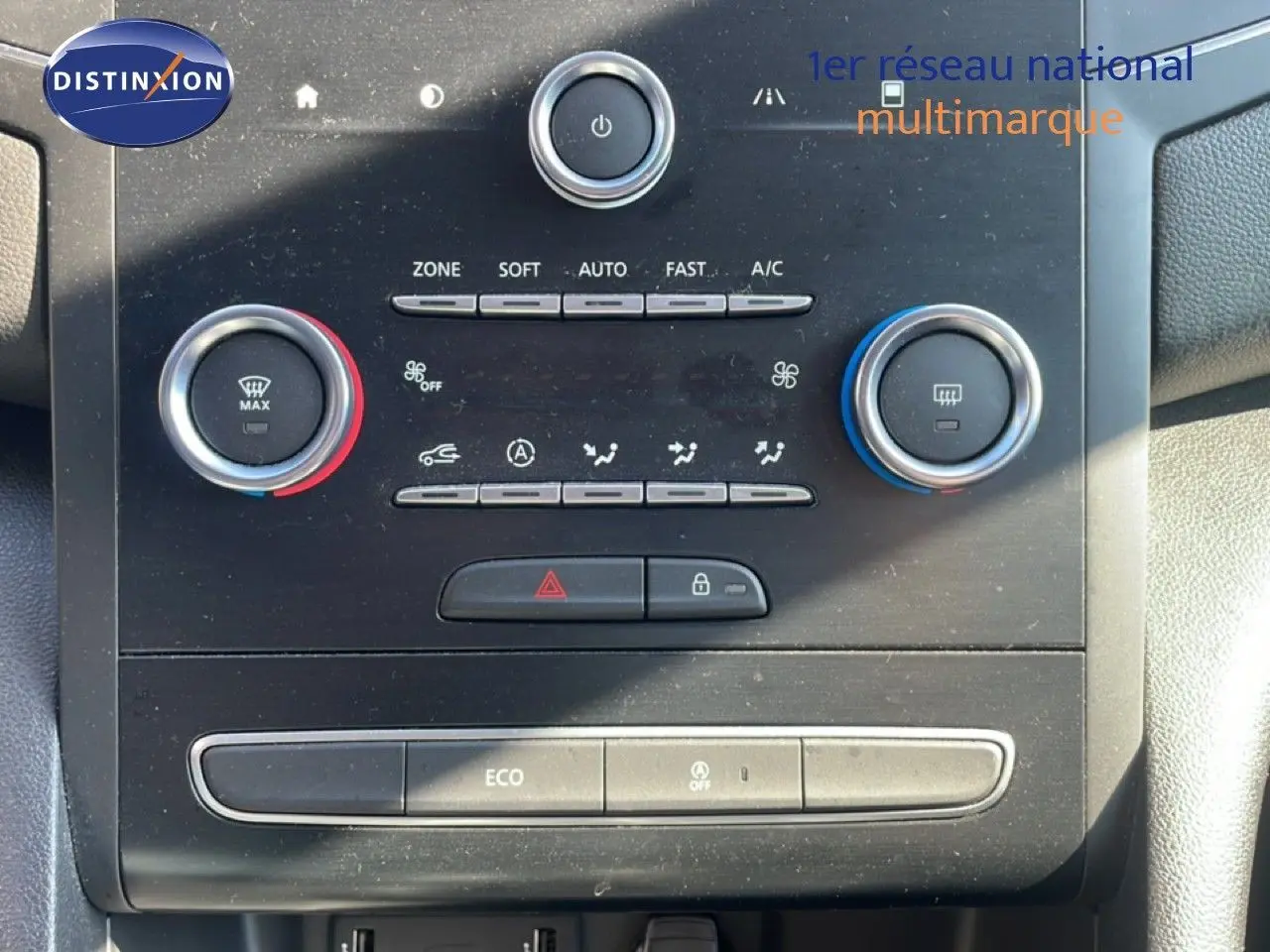 Détail du tableau de bord de la Renault Mégane 2019, montrant les commandes de climatisation avec boutons rotatifs rouge et bleu.