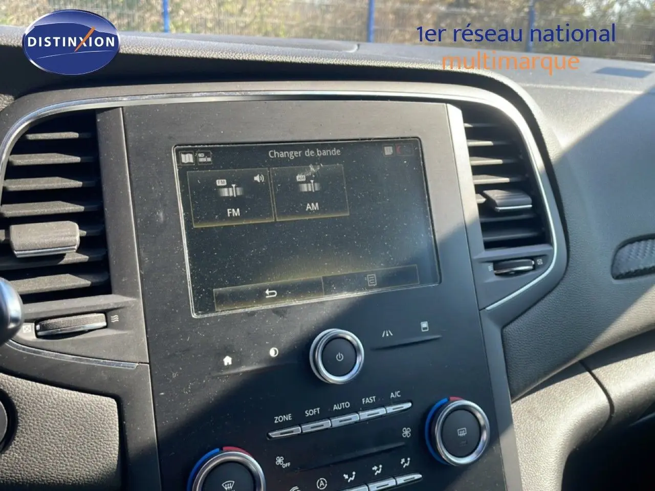 Vue rapprochée du tableau de bord de la Renault Mégane 2019, avec écran tactile et commandes de climatisation visibles.