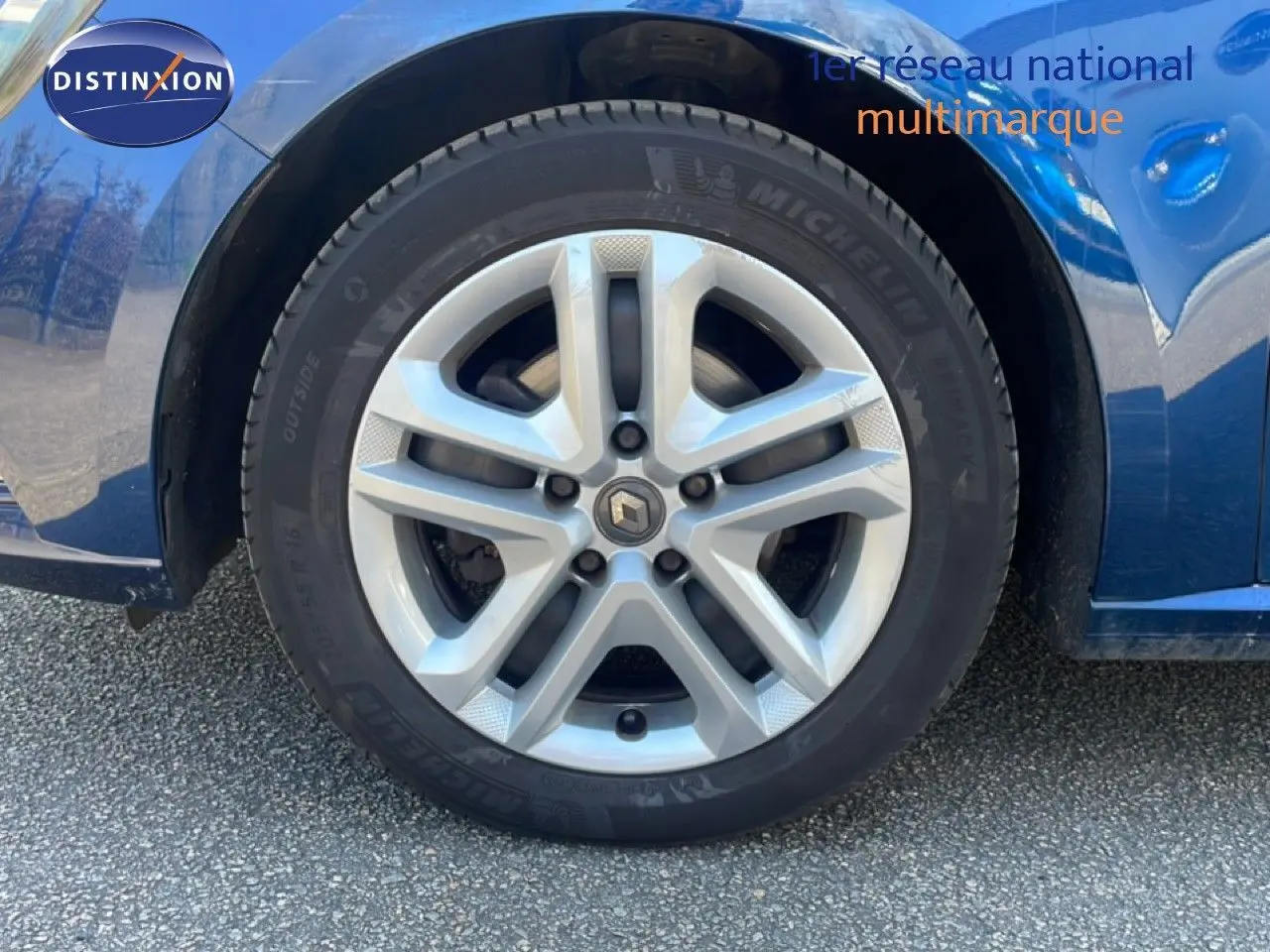 Gros plan sur la roue avant droite d'une Renault Mégane bleu cosmos métal, mettant en valeur la jante alliage et le pneu Michelin.