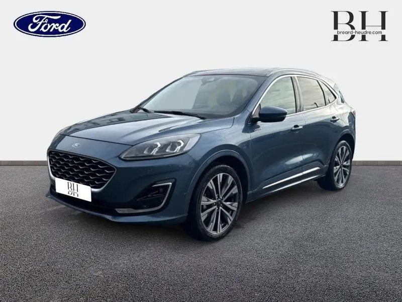 Ford Kuga 2023 bleu azur métallisé en vue 3/4 avant, avec jantes alliage 20 pouces et toit panoramique électrique.