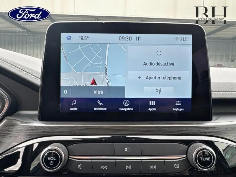 Écran tactile central du Ford Kuga 2023 affichant la navigation, avec commandes audio et finition bois sombre.