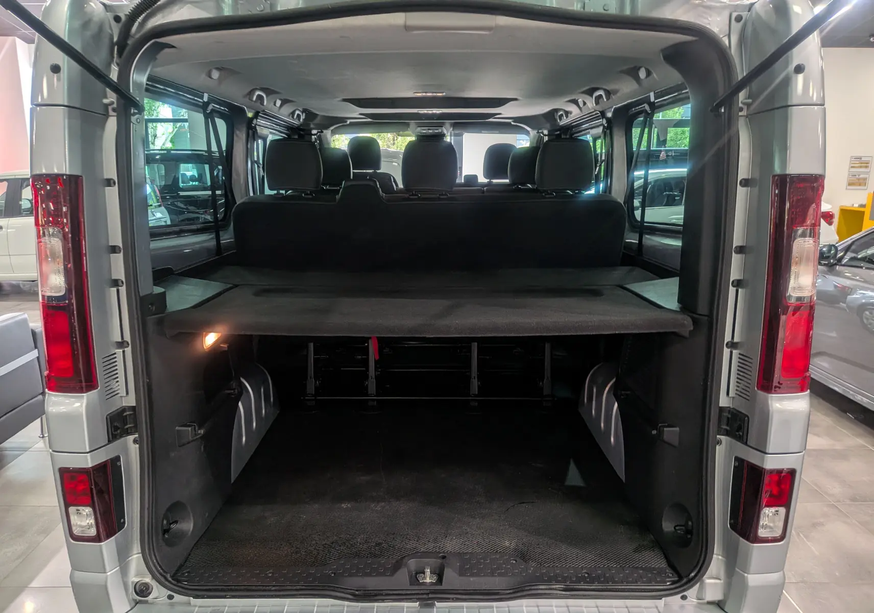 Vue arrière ouverte du Nissan Primastar Combi gris Highland 2026, montrant l'espace de chargement et les sièges arrière.