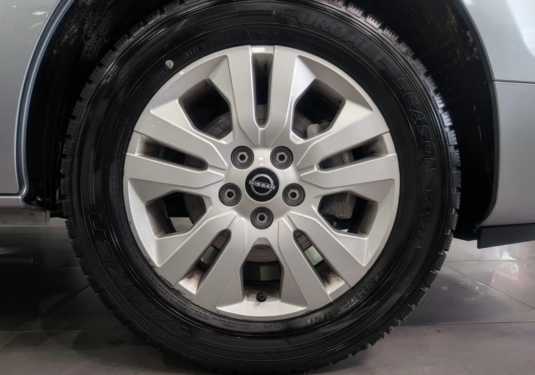 Gros plan sur la jante alliage argentée du Nissan Primastar Combi gris Highland, mettant en valeur le logo central Nissan.