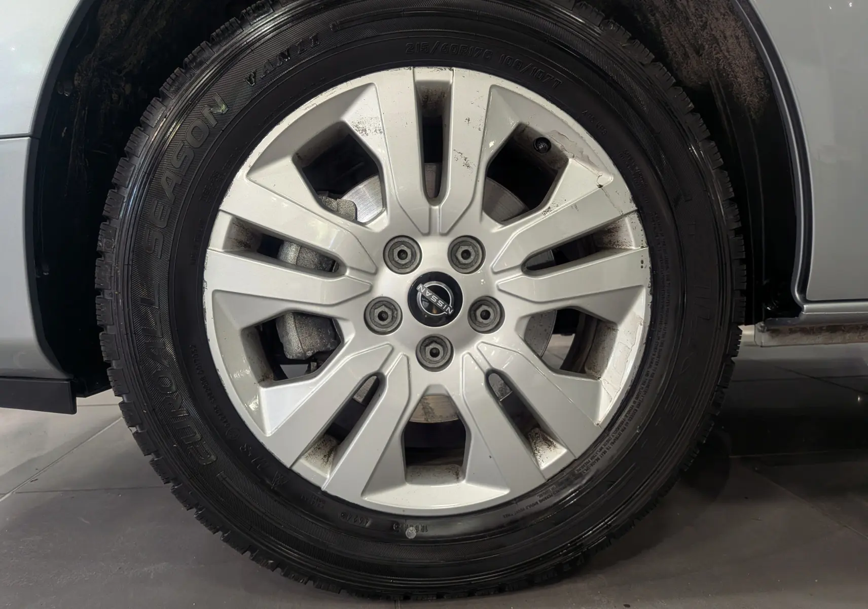 Gros plan sur la roue avant droite gris Highland d’un Nissan Primastar Combi 2026 avec jante alliage et logo Nissan central.