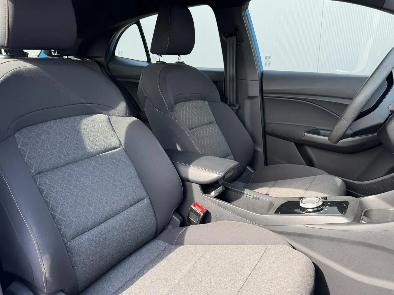 Vue intérieure côté conducteur du MG3 1.5 Hybrid+ 195 Comfort, sièges tissu noir avec accoudoir central et console moderne.