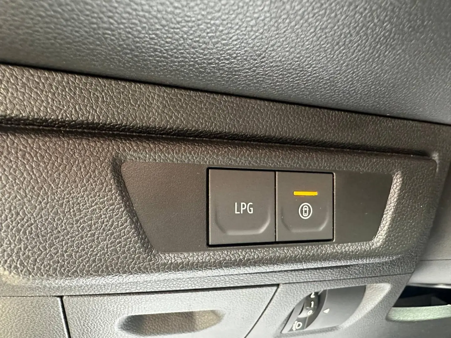 Gros plan sur les boutons LPG et verrouillage centralisé sur la planche de bord noire du Dacia Jogger 2025.