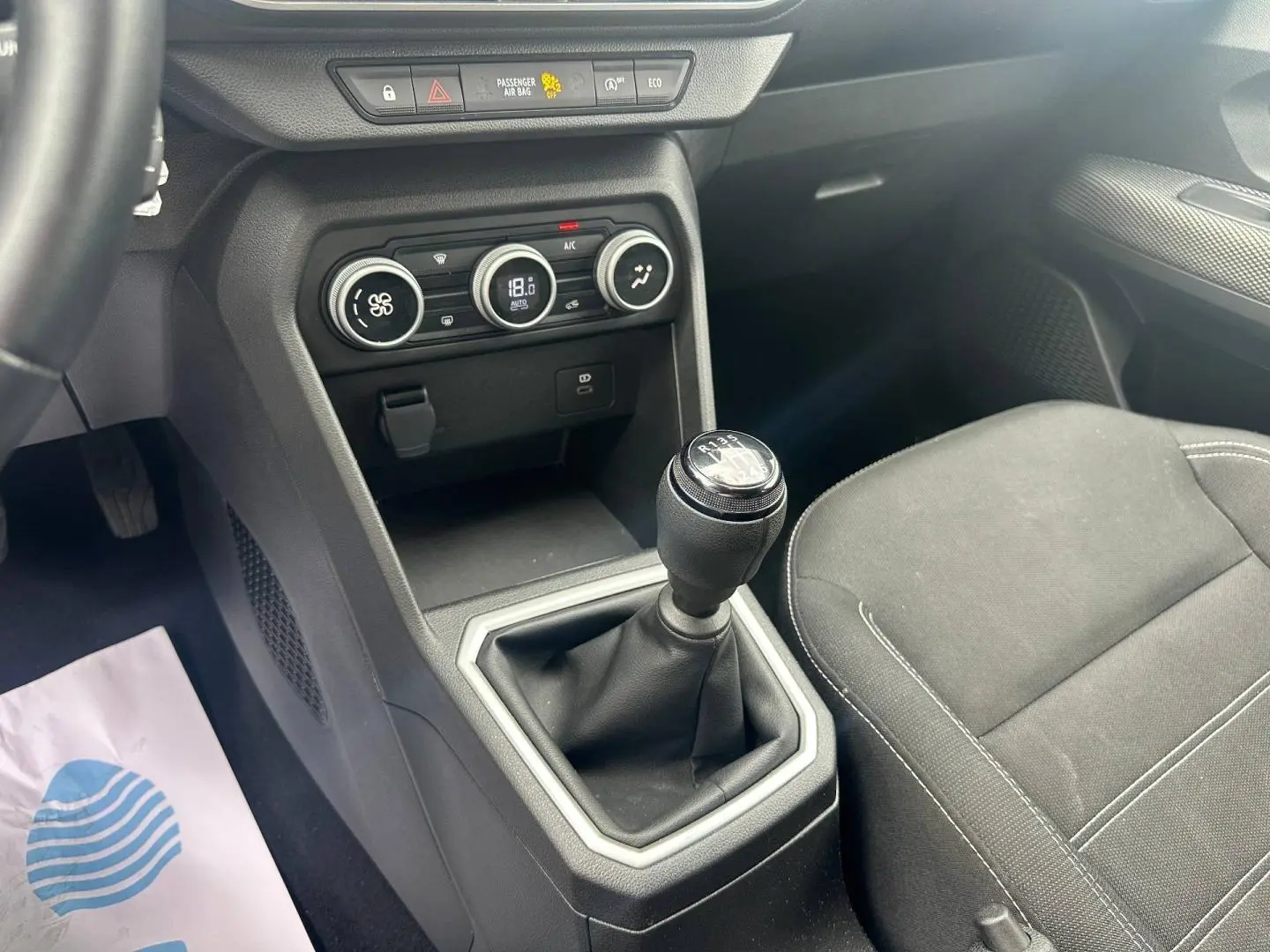 Vue intérieure centrée sur la console centrale et levier de vitesse manuel du Dacia Jogger, sièges tissu noir.