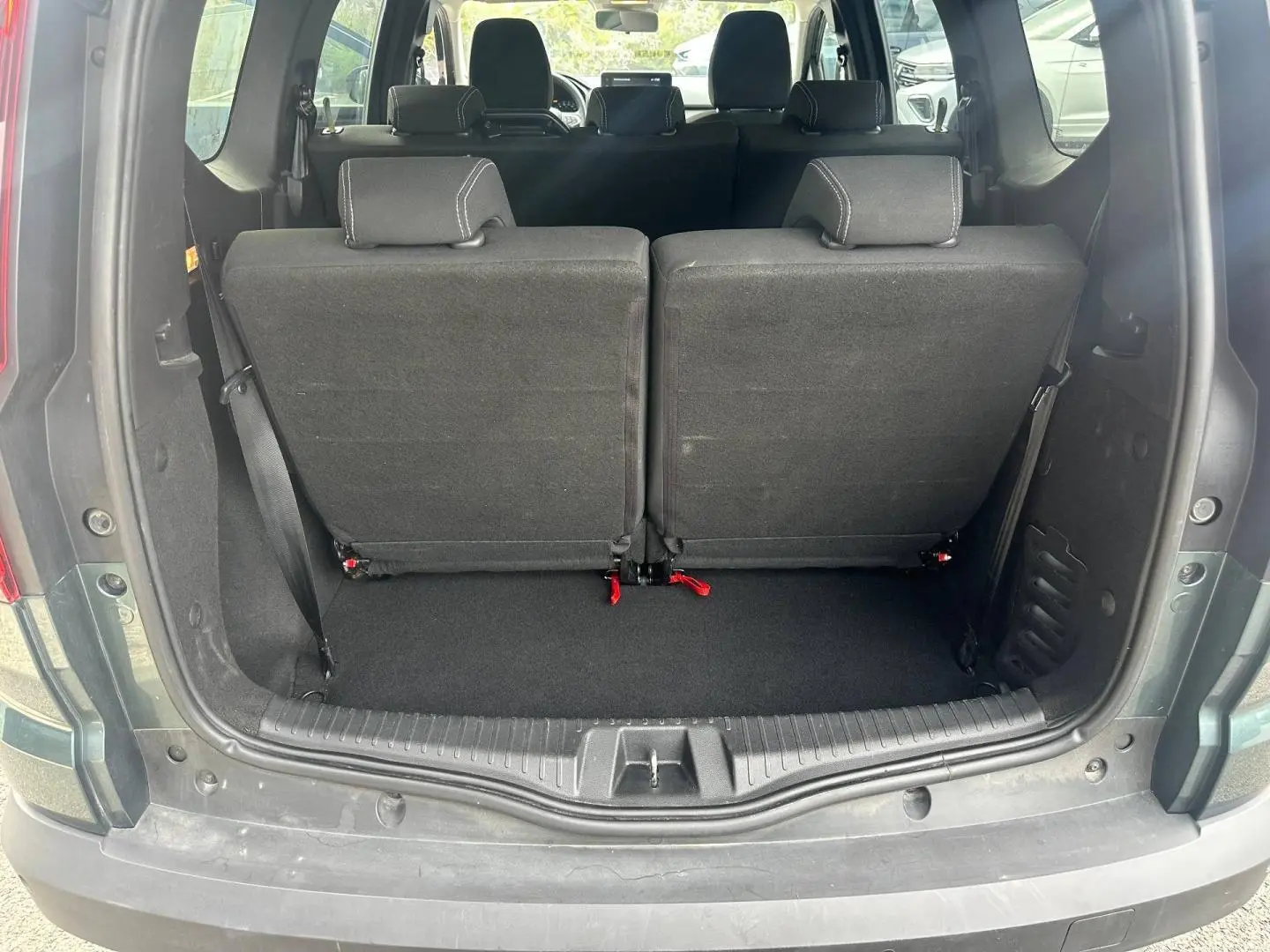 Vue arrière du coffre du Dacia Jogger vert cèdre métallisé avec la troisième rangée de sièges relevée en tissu noir.