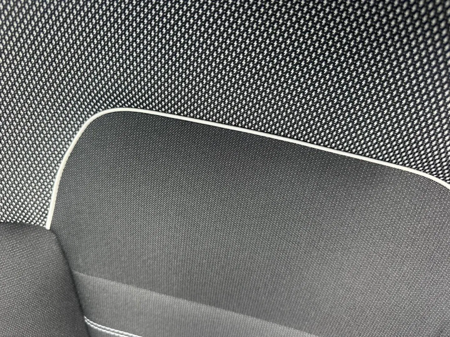 Gros plan sur le tissu noir à motif gris clair avec surpiqûres blanches, intérieur du siège Dacia Jogger Expression.