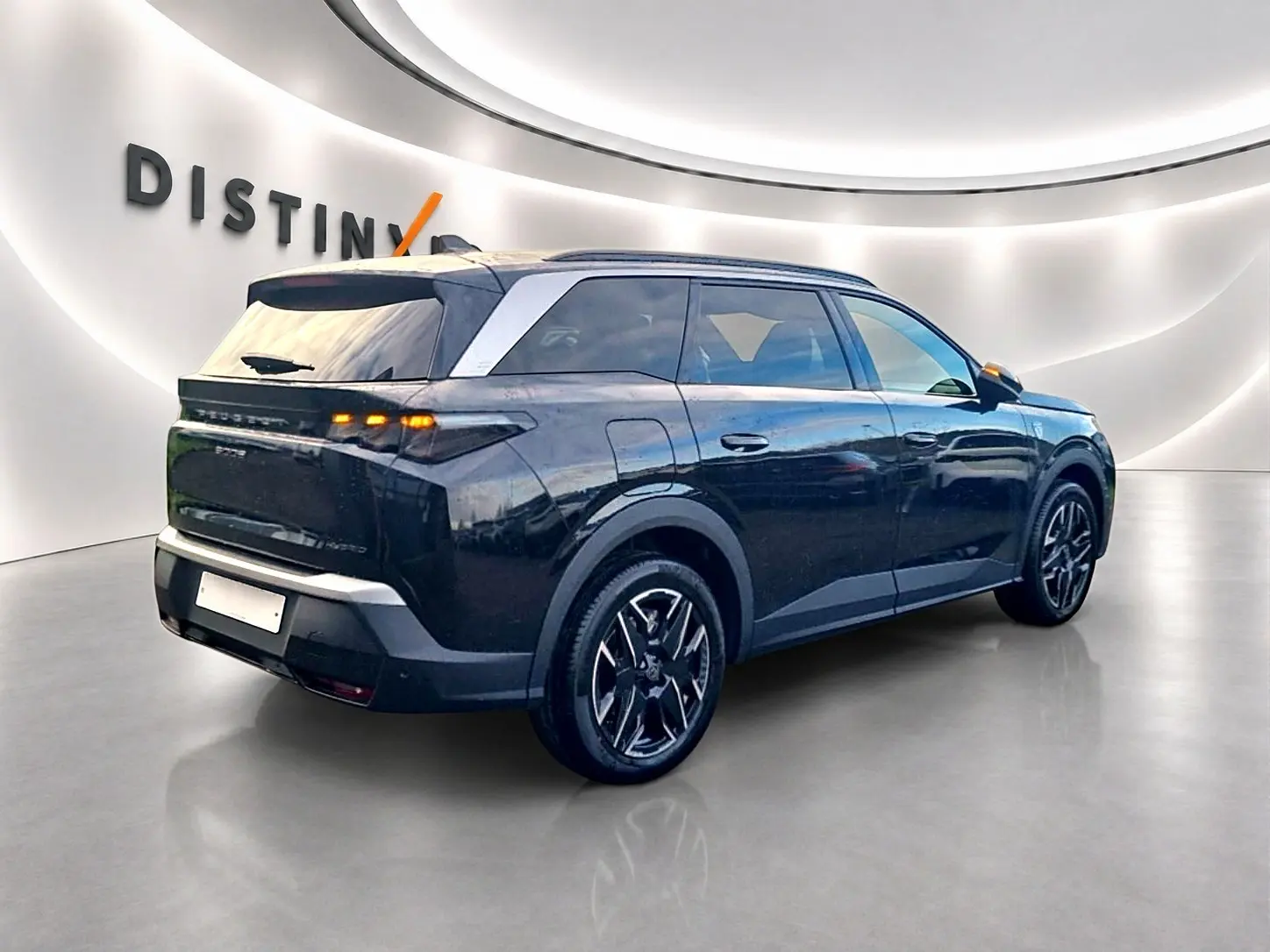 Peugeot 5008 Hybrid 145 GT noir vu en 3/4 arrière droit avec jantes alu et vitres surteintées dans un showroom.