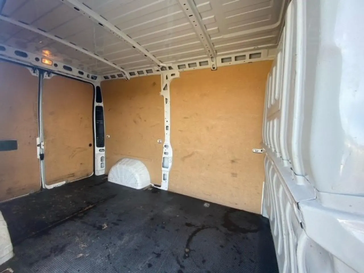 Intérieur du fourgon blanc Peugeot Boxer III 330 L2H2, vue vers l'arrière avec parois en bois et sol noir.