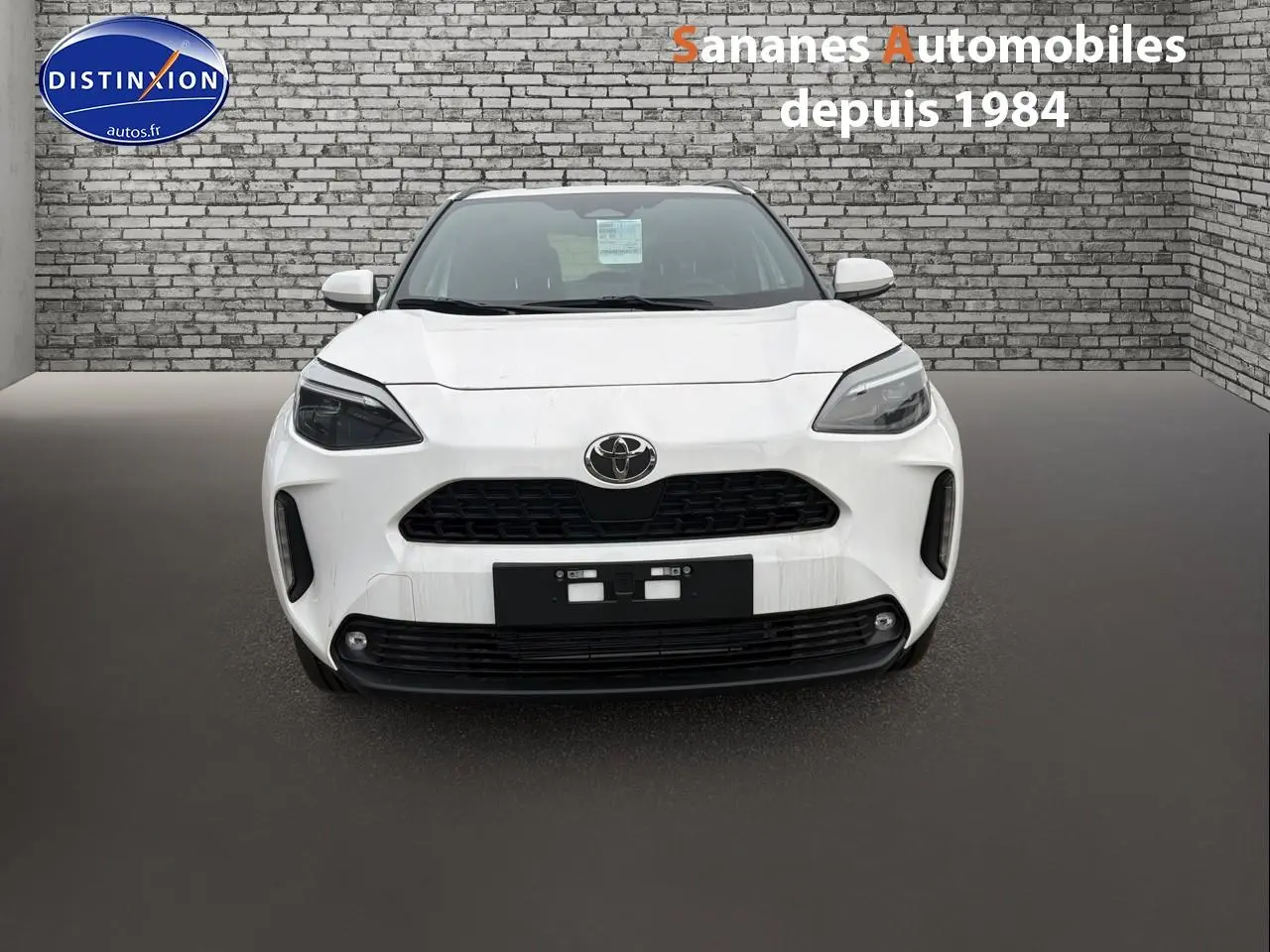 Vue frontale d'une Toyota Yaris Cross Hybrid 130h blanche, avec calandre noire et phares LED marqués.