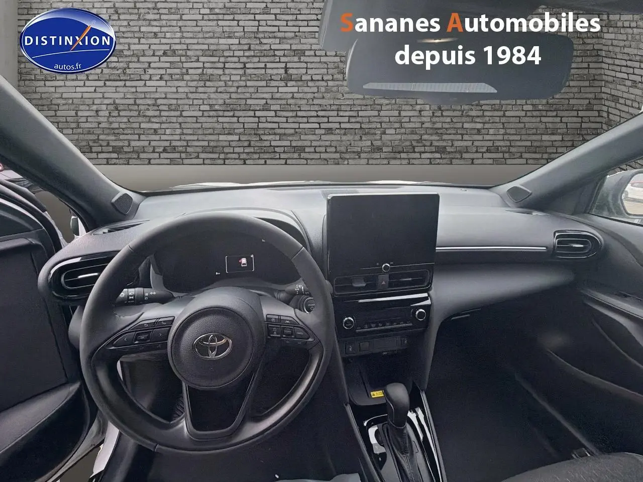 Vue intérieure avant de la Toyota Yaris Cross Hybrid 130h 2025, tableau de bord noir avec écran tactile central.