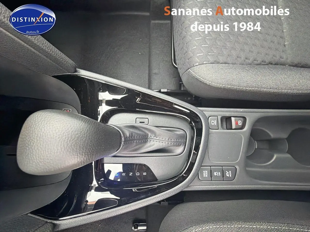 Vue plongeante sur le levier de vitesses automatique et la console centrale noire de la Toyota Yaris Cross Hybrid 130h blanche.