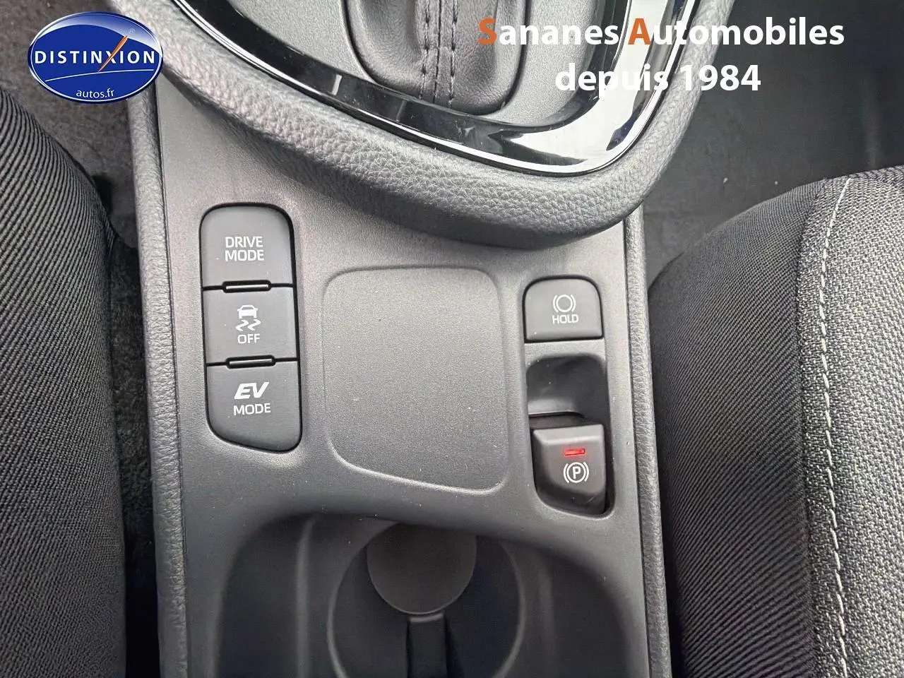 Vue rapprochée du panneau de commandes central de la Toyota Yaris Cross Hybrid 130h blanc, avec boutons Drive Mode et frein de parking électronique.