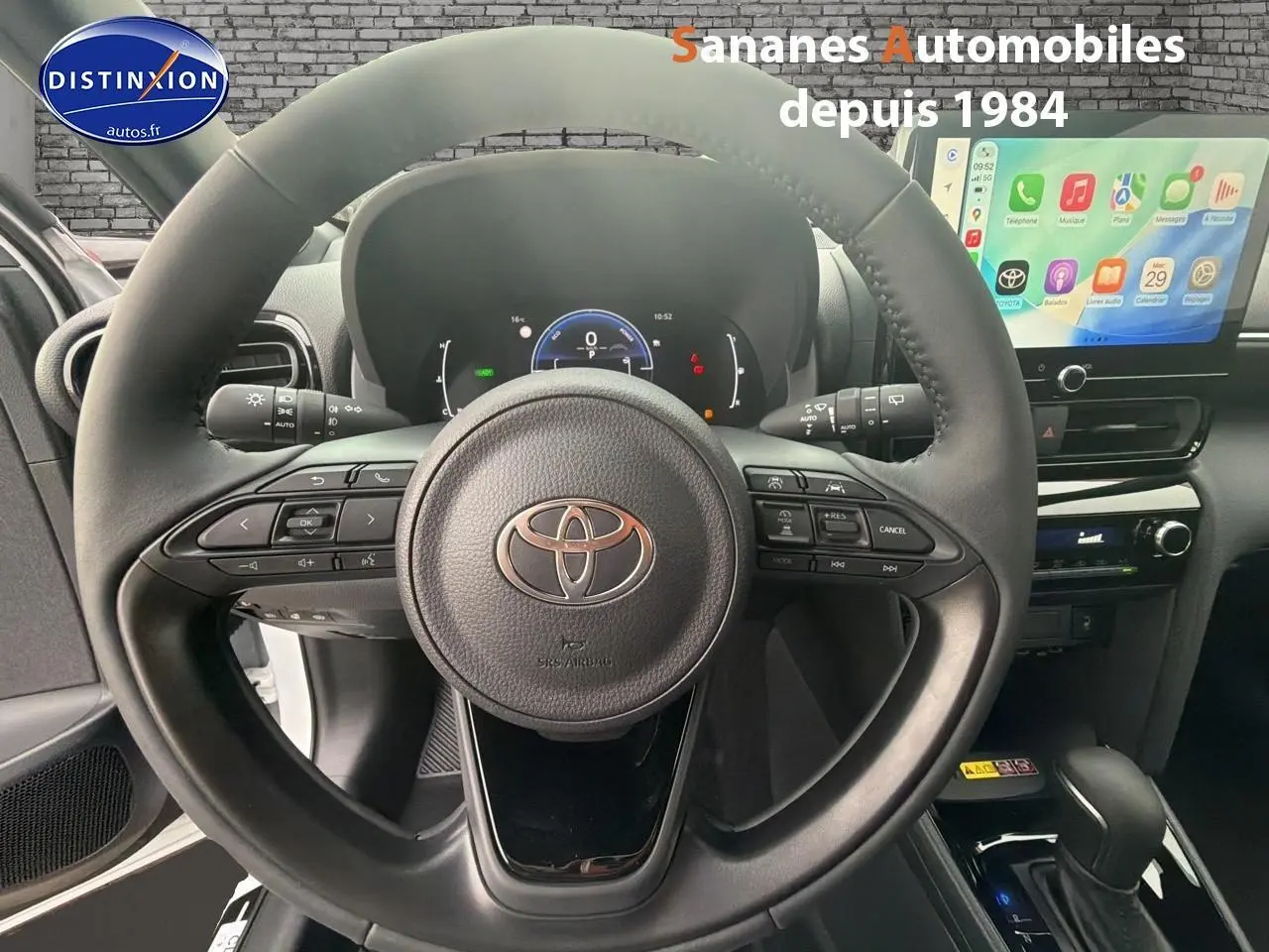 Vue intérieure centrée sur le volant de la Toyota Yaris Cross Hybrid 130h 2025 avec écran tactile et commandes au volant.