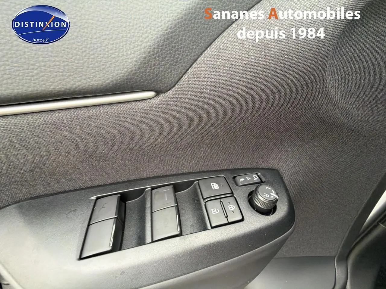 Gros plan sur les commandes de lève-vitres et rétroviseurs côté conducteur de la Toyota Yaris Cross blanche hybride 2025.