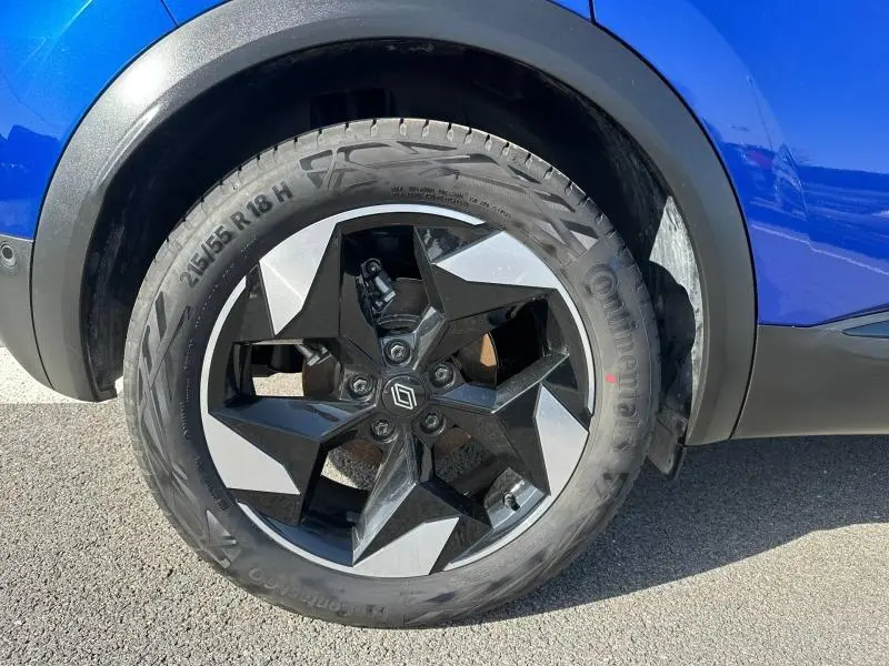 Gros plan sur la roue arrière droite du Renault Captur 2025 Bleu Iron avec jante noire et grise au design étoilé.