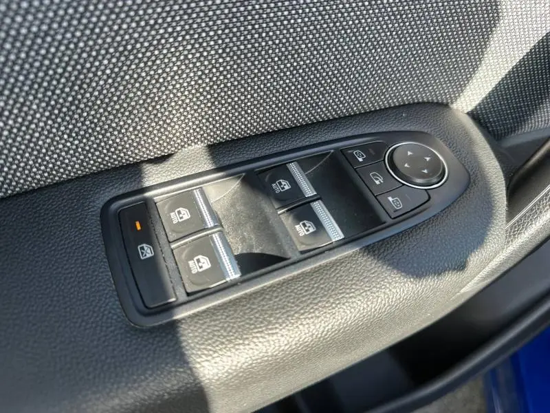 Gros plan sur les commandes des vitres électriques côté conducteur du Renault Captur 2025 Bleu Iron/Noir Étoilé.