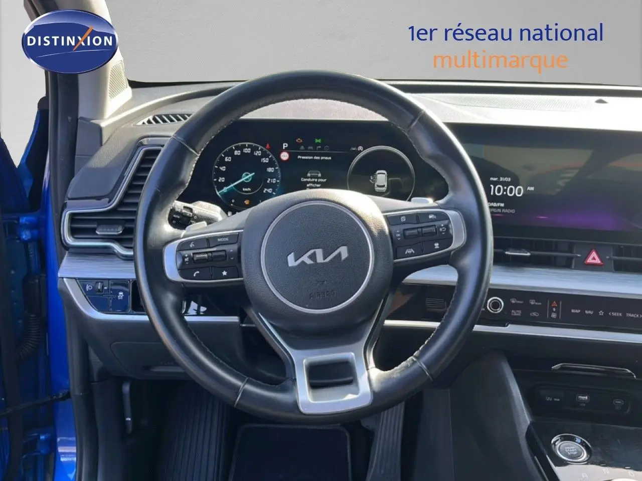 Vue intérieure centrée sur le volant cuir noir du Kia Sportage 2022, avec tableau de bord digital et écran tactile.