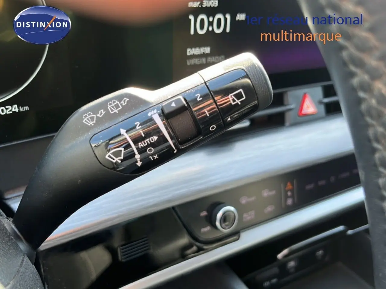 Gros plan sur la commande d’essuie-glace du Kia Sportage bleu fusion métal, avec tableau de bord numérique en arrière-plan.