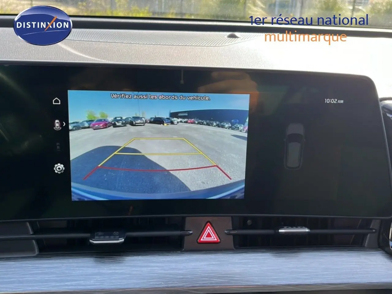 Écran central du Kia Sportage 2022 bleu fusion, affichant la caméra de recul avec lignes de guidage colorées.