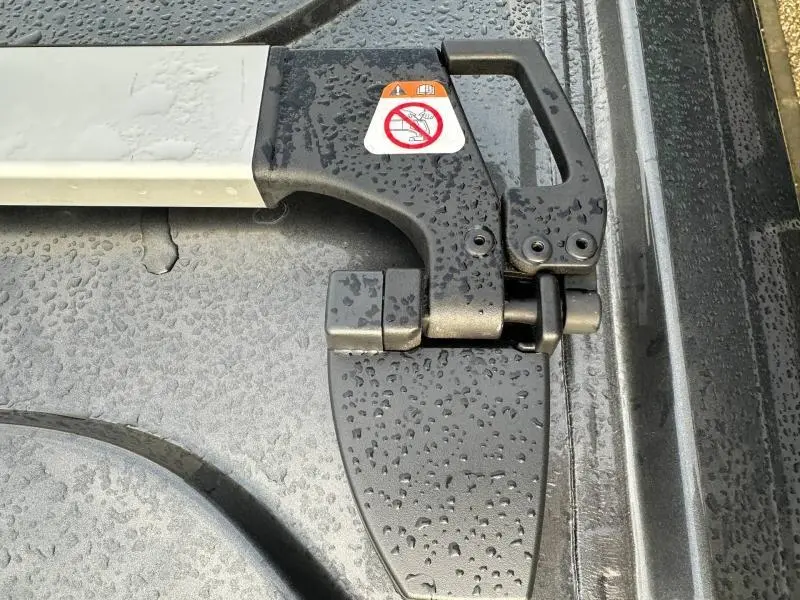 Gros plan sur la poignée de verrouillage noire avec gouttes d'eau du hayon arrière du Volkswagen Transporter FGN gris 2025.