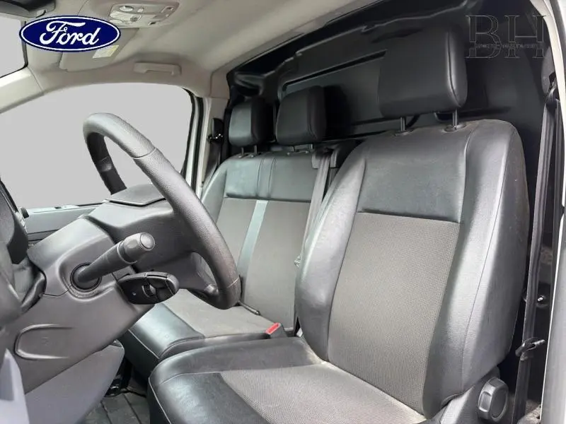 Vue intérieure côté conducteur du Citroën Jumpy blanc Banquise 2021, montrant les sièges avant en tissu et cuir noir.