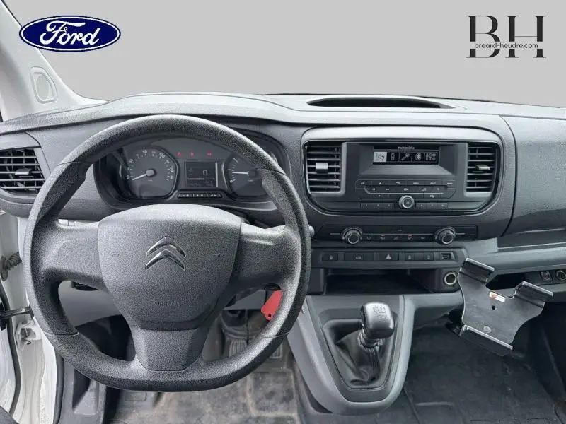 Vue intérieure frontale du Citroën Jumpy blanc Banquise 2021, volant, tableau de bord et boîte manuelle visibles.