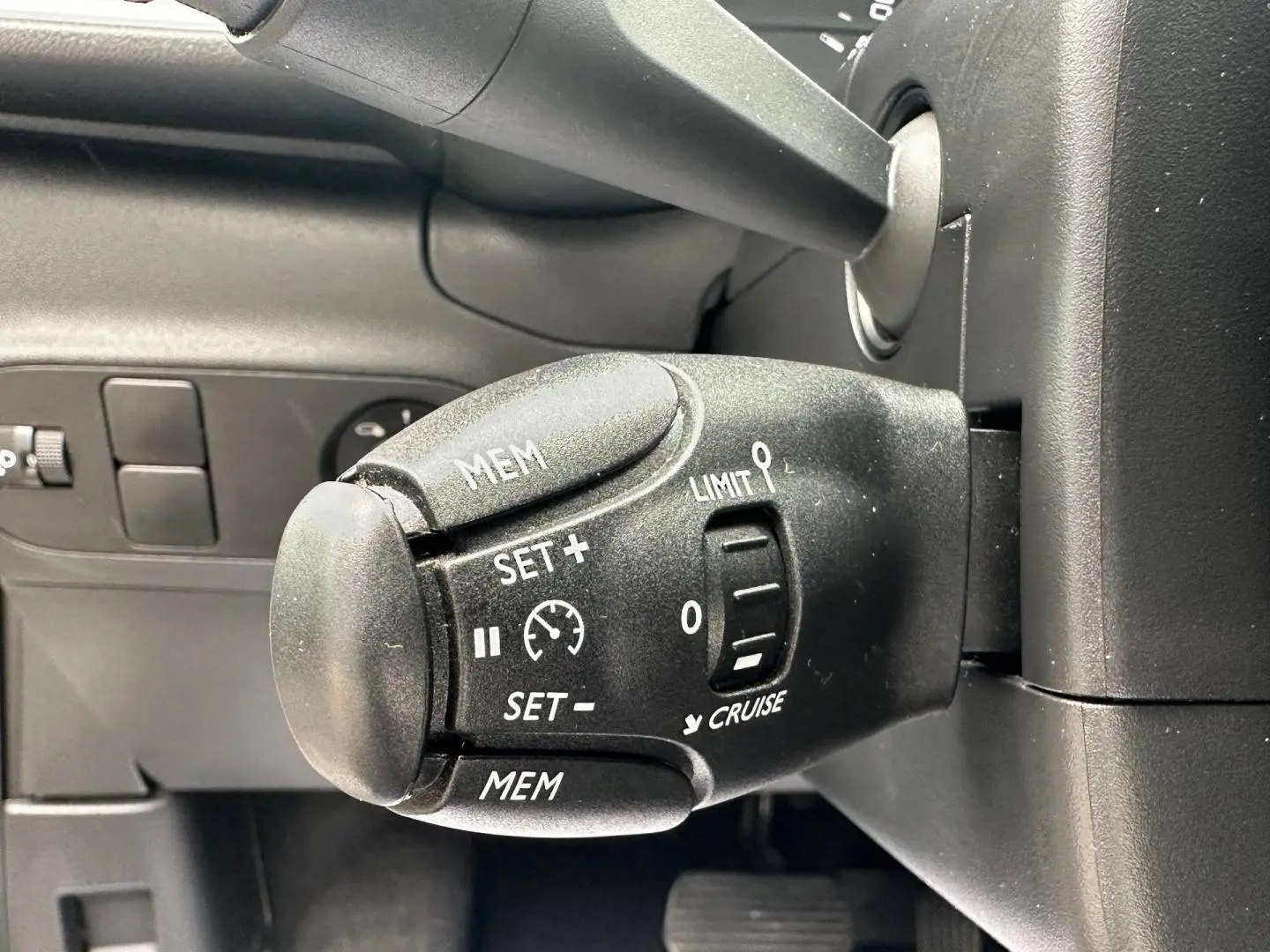 Gros plan sur la commande de régulateur de vitesse noire dans l’habitacle d’une Citroën C3 blanche Banquise 2023.